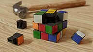 Blender3D rendering of a partially disassembled Rubiks Cube next to a hammer